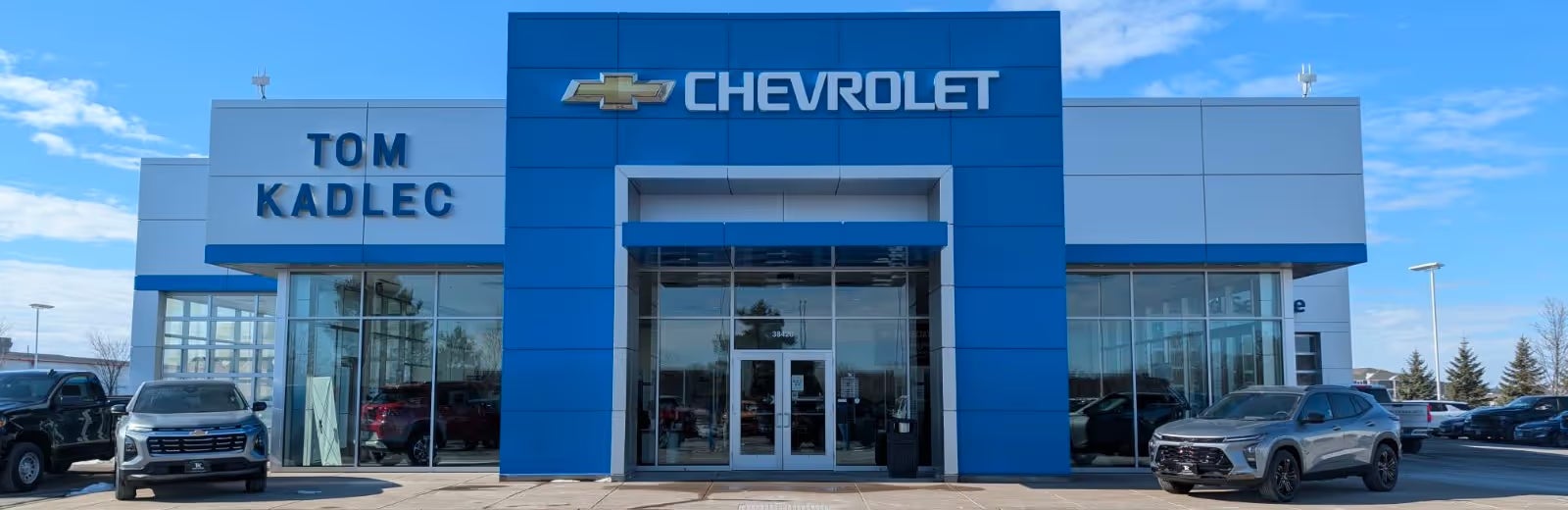 Exterior of a Chevrolet dealership, TOM KADLEC on the left and a large CHEVROLET sign in the center.